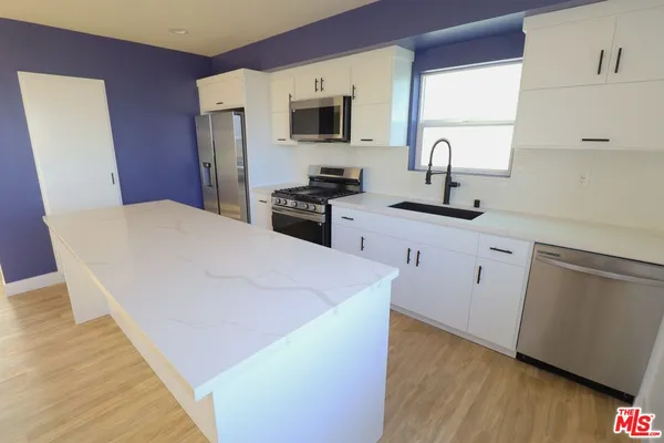 a kitchen with stainless steel appliances a refrigerator sink and wooden floor