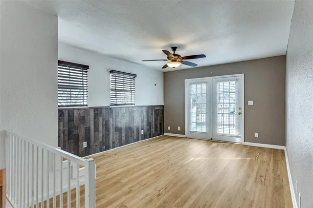 a view of an empty room with a window and wooden floor