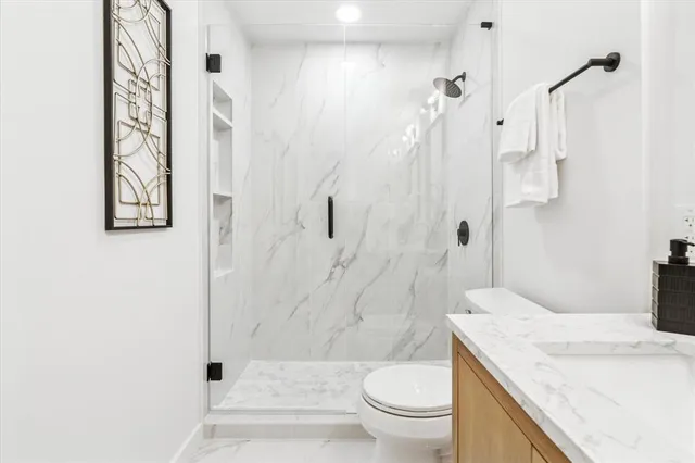 a bathroom with a granite countertop sink toilet and shower