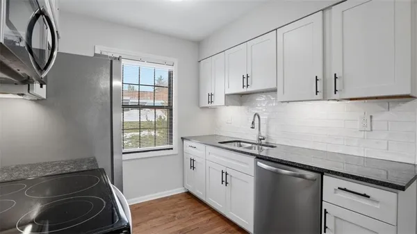 a kitchen with granite countertop a sink a stove and cabinets