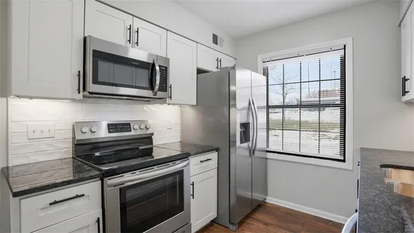 a kitchen with stainless steel appliances white cabinets and a stove top oven
