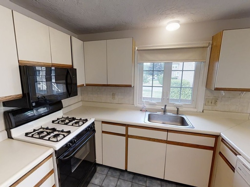 61 Heritage Drive, Unit 61 Tewksbury, MA 01876 - Photo 8 of 35 a kitchen with granite countertop a sink stove and cabinets