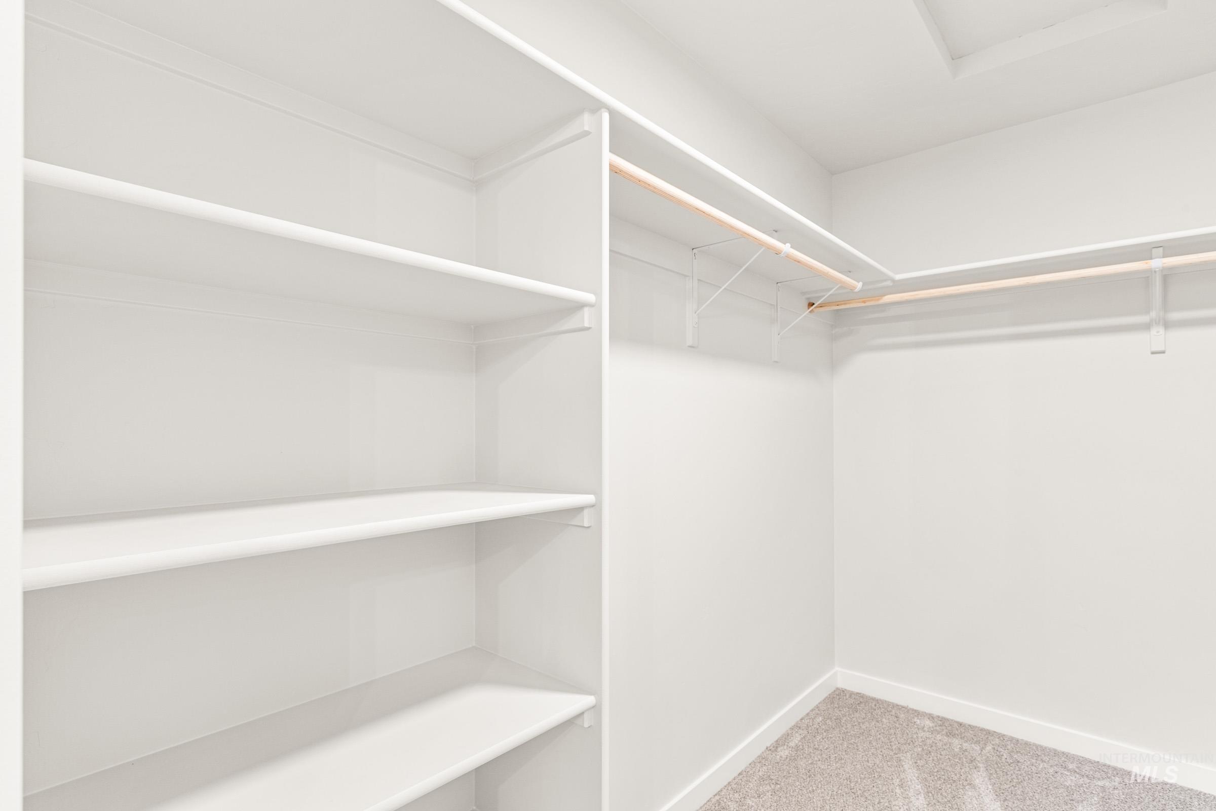 1077 West Jasper Street Meridian, ID 83642 - Photo 18 of 19 Bright walk-in closet featuring white built-in shelving, multiple hanging rods, and light-toned carpeting