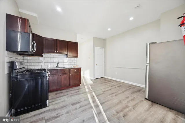 a kitchen with stainless steel appliances granite countertop a stove a sink and a refrigerator with wooden floor