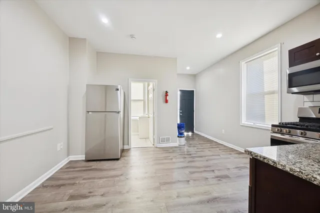 a view of kitchen with stainless steel appliances granite countertop a refrigerator and a stove top oven
