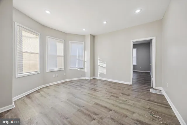 an empty room with wooden floor and windows