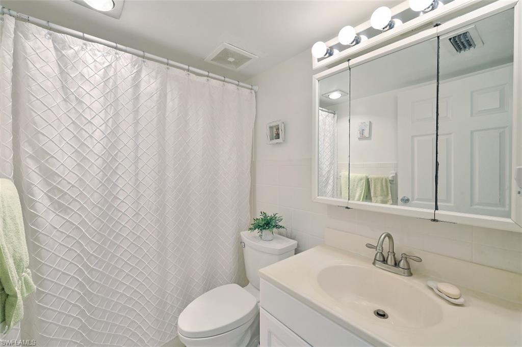 1010 Manatee Road, Unit B201 Naples, FL 34114 - Photo 14 of 24 a bathroom with a sink a toilet and shower curtain