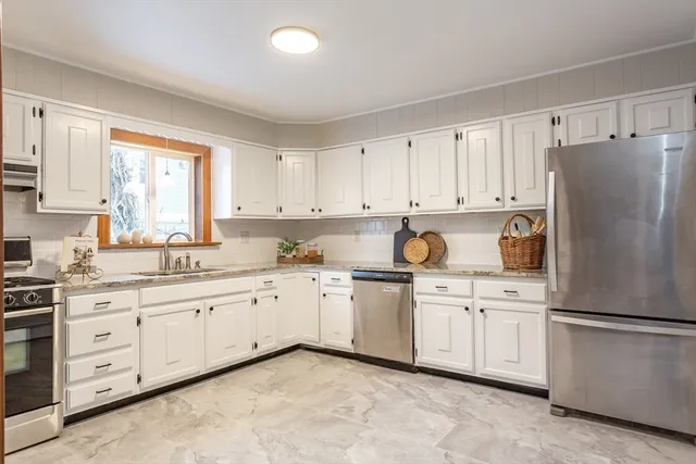 a kitchen with granite countertop white cabinets and white stainless steel appliances