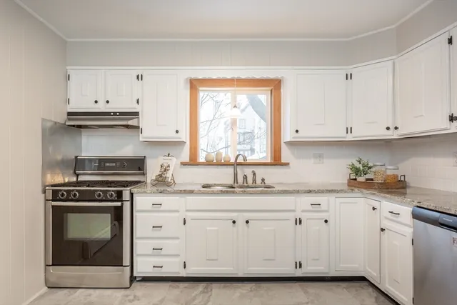 a kitchen with granite countertop white cabinets and stainless steel appliances