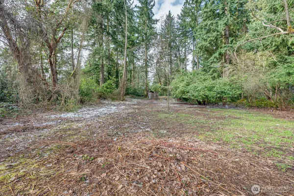 a view of a house with large trees and wooden fence