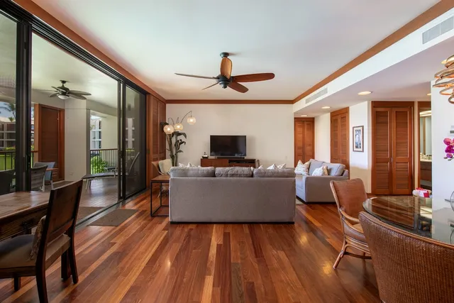 a living room with couches a flat screen tv and kitchen view