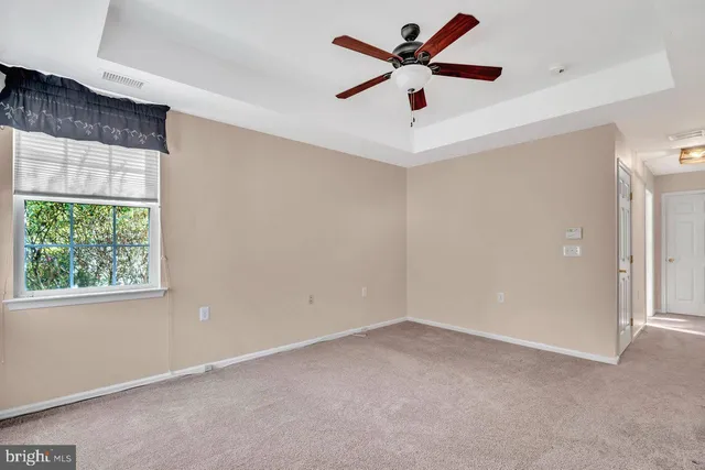 an empty room with a window and a fan