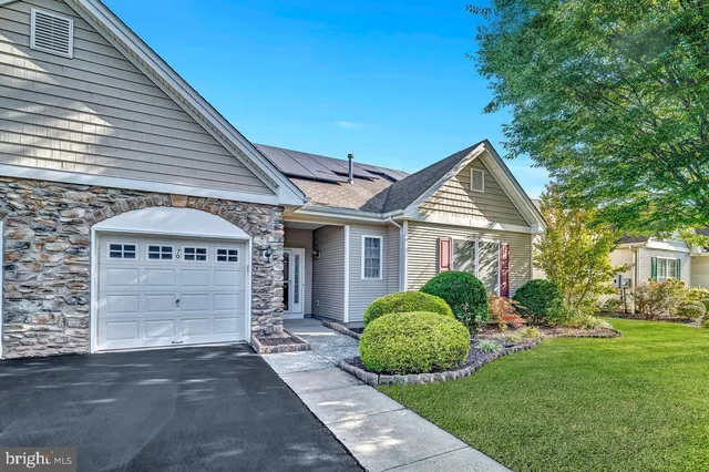 a view of a house with a small yard plants and large tree