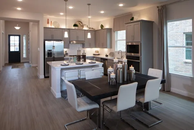 a dining room with furniture a wooden floor and a kitchen view