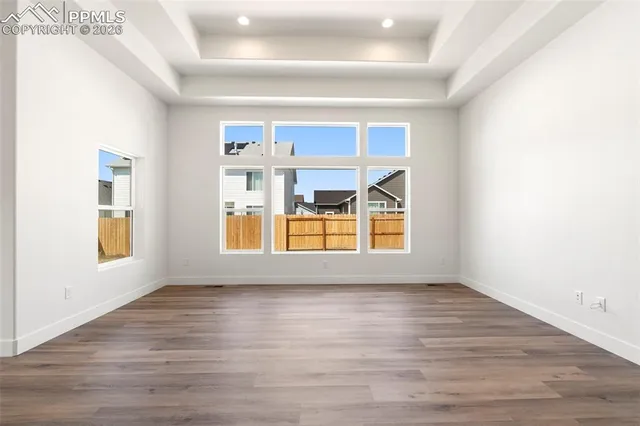 a view of an empty room with a window and wooden floor