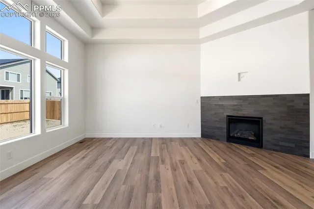 an empty room with wooden floor fireplace and windows
