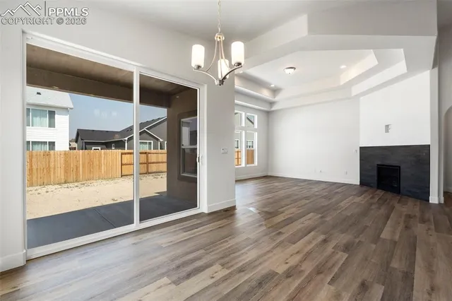 an empty room with wooden floor fireplace and windows