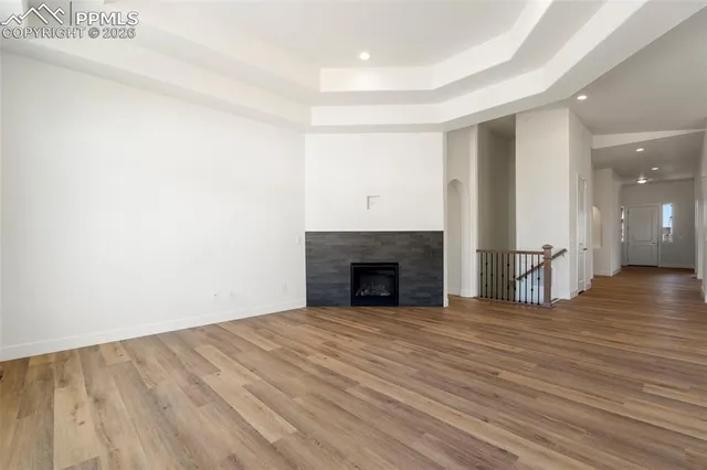a view of an empty room with wooden floor and a fireplace