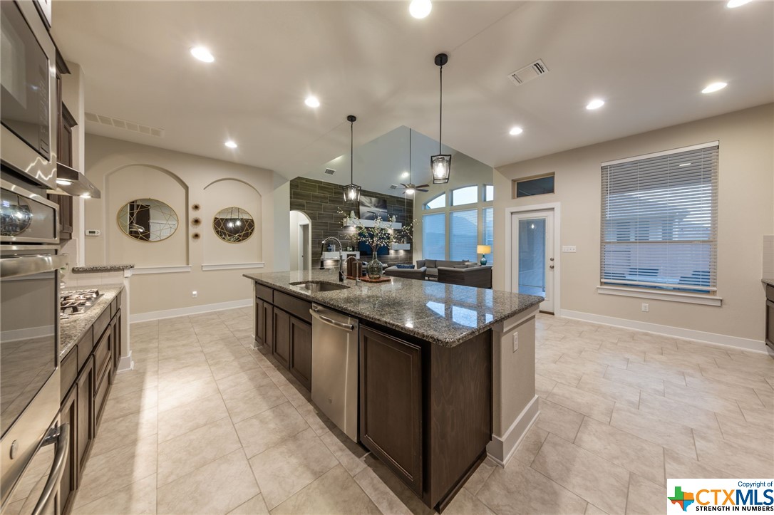 a kitchen with stainless steel appliances granite countertop a sink and a stove