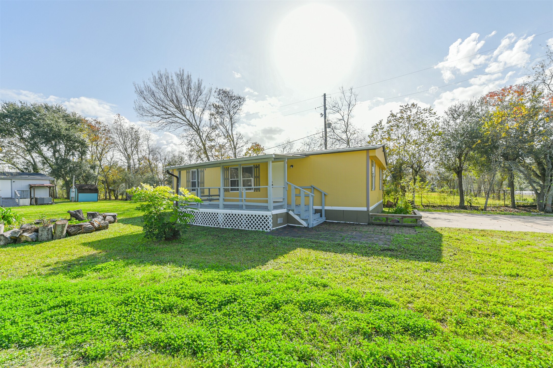 Charming yellow home with a cozy front porch, nestled on a spacious, grassy lot. Surrounded by mature trees, it offers a serene country feel with plenty of outdoor space.