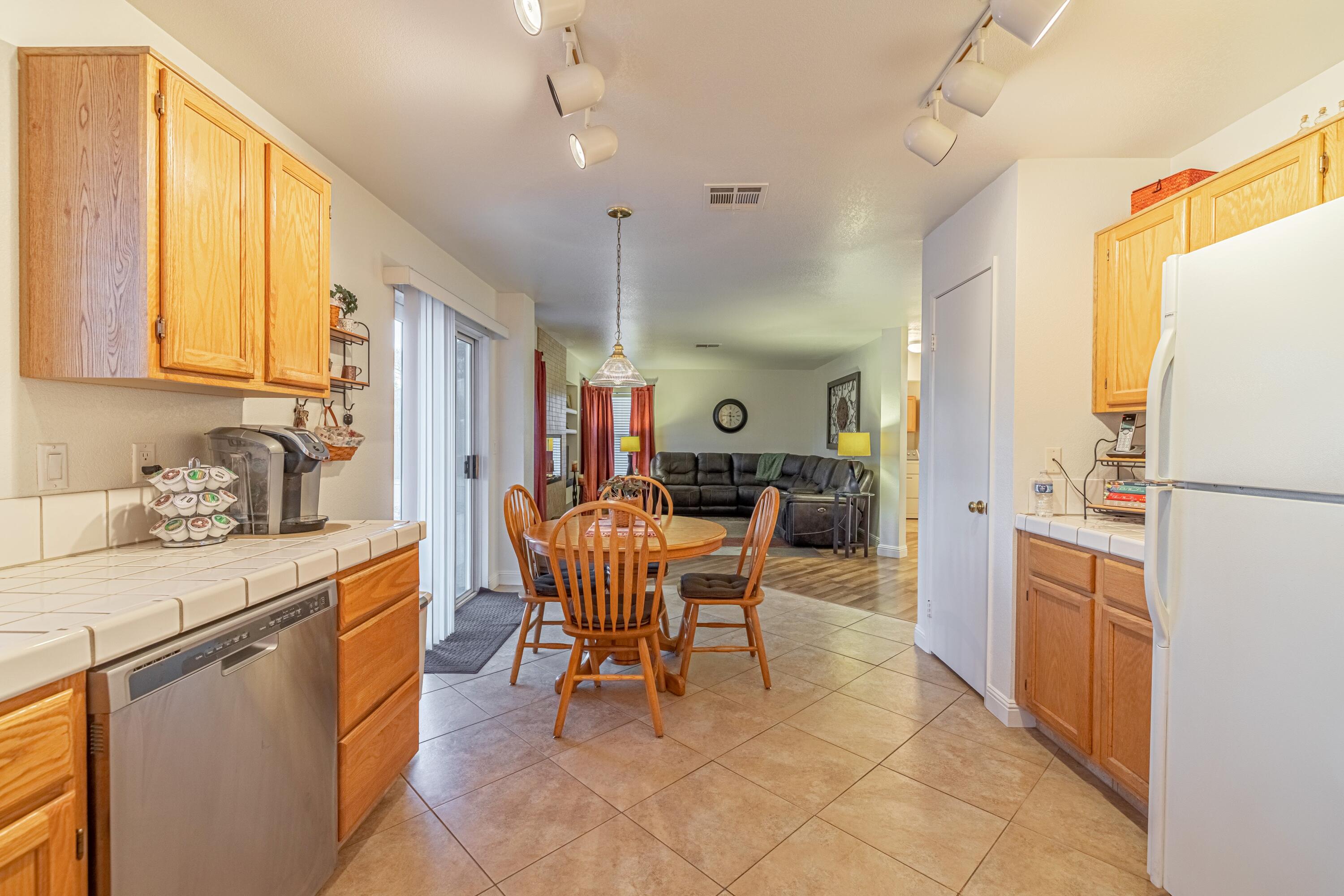 44220 Encanto Way Lancaster, CA 93536 - Photo 9 of 45 a kitchen with a refrigerator a stove top oven a sink dishwasher and dining table with wooden floor