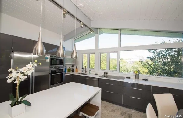 a kitchen with stainless steel appliances kitchen island granite countertop a sink stove and refrigerator
