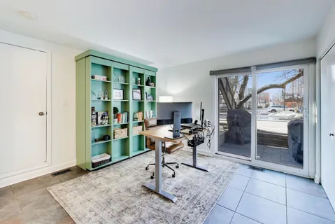 a work room with furniture a rug and a window