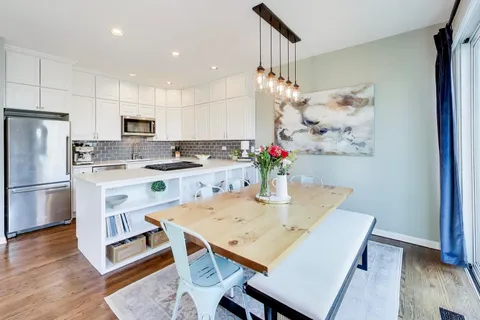 a kitchen with stainless steel appliances granite countertop a sink a stove a refrigerator and a dining table