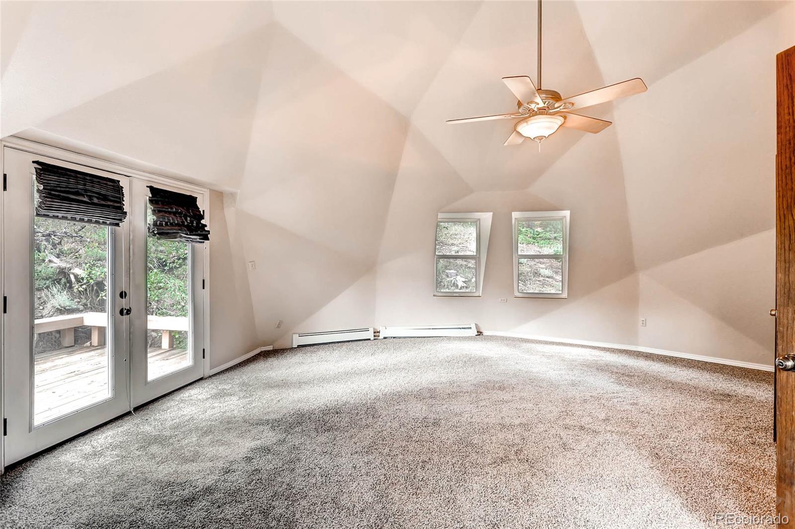 11648 Ranch Elsie Road Golden, CO 80403 - Photo 7 of 13 an empty room with windows and chandelier fan