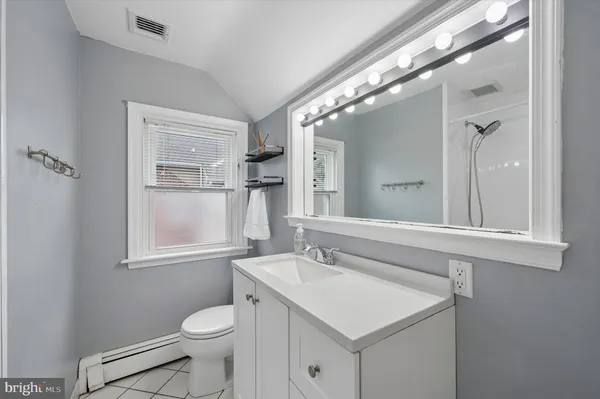 a bathroom with a sink a toilet a mirror and a window