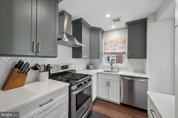 a kitchen with stainless steel appliances white cabinets and a stove top oven