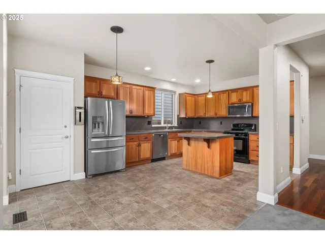 a kitchen with stainless steel appliances kitchen island granite countertop a refrigerator a stove a sink and a microwave