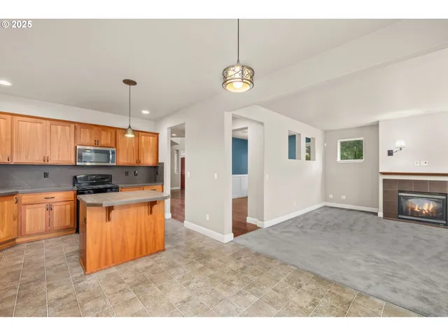 a kitchen with stainless steel appliances granite countertop a refrigerator a sink dishwasher a stove and a dining table with wooden floor