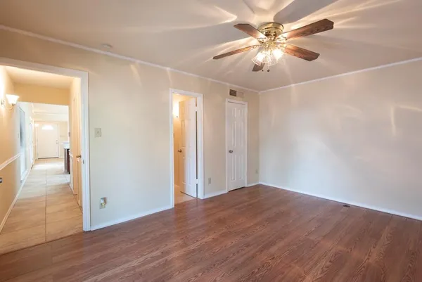 a view of an empty room and chandelier fan