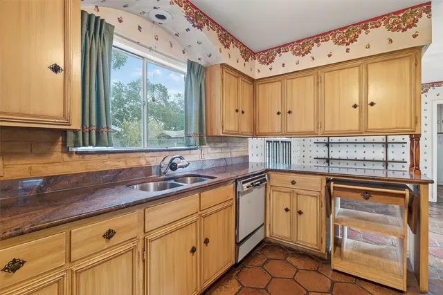 a kitchen with granite countertop a sink stainless steel appliances white cabinets and a window