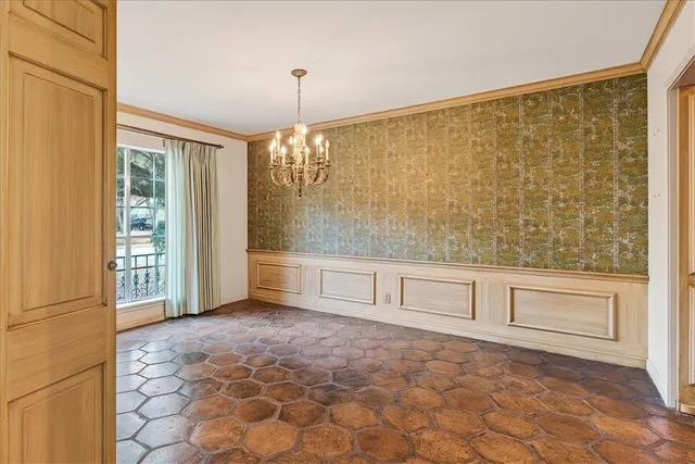 a view of an empty room with cabinet and chandelier