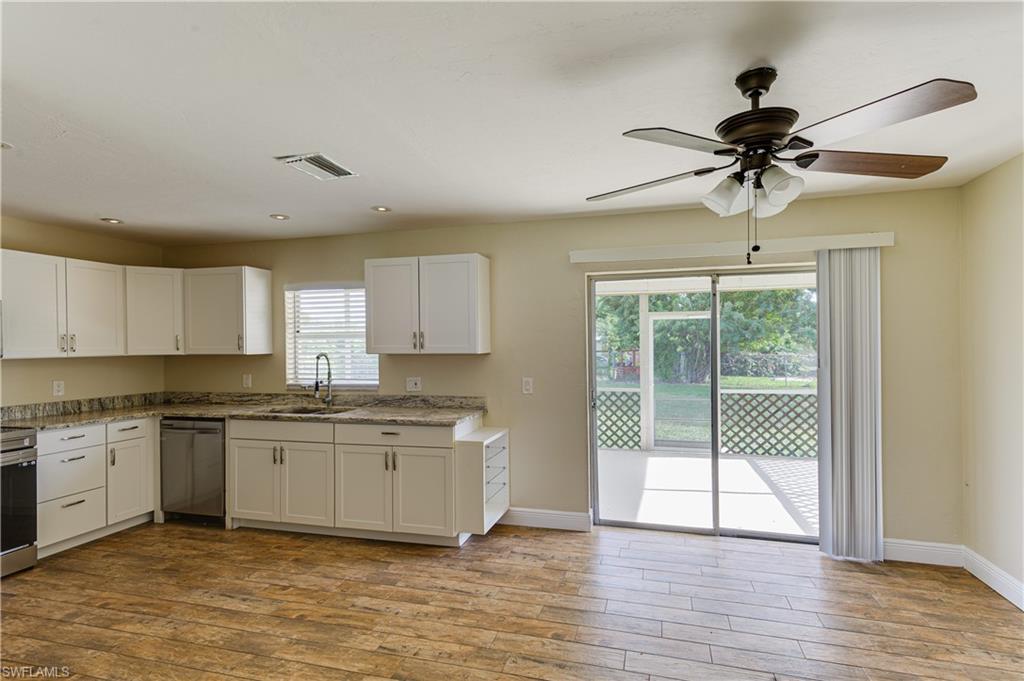 Undisclosed Address Naples, FL 34116 - Photo 9 of 18 a kitchen with stainless steel appliances granite countertop a stove a sink and white cabinets with wooden floors