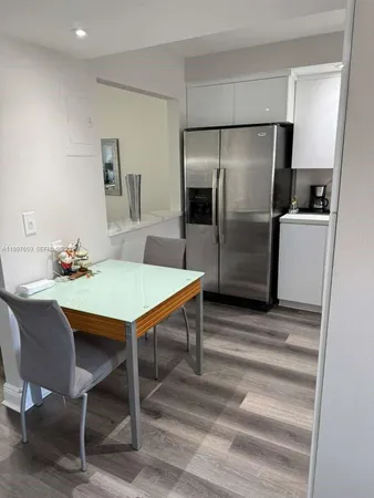a kitchen with stainless steel appliances refrigerator dining table and chairs