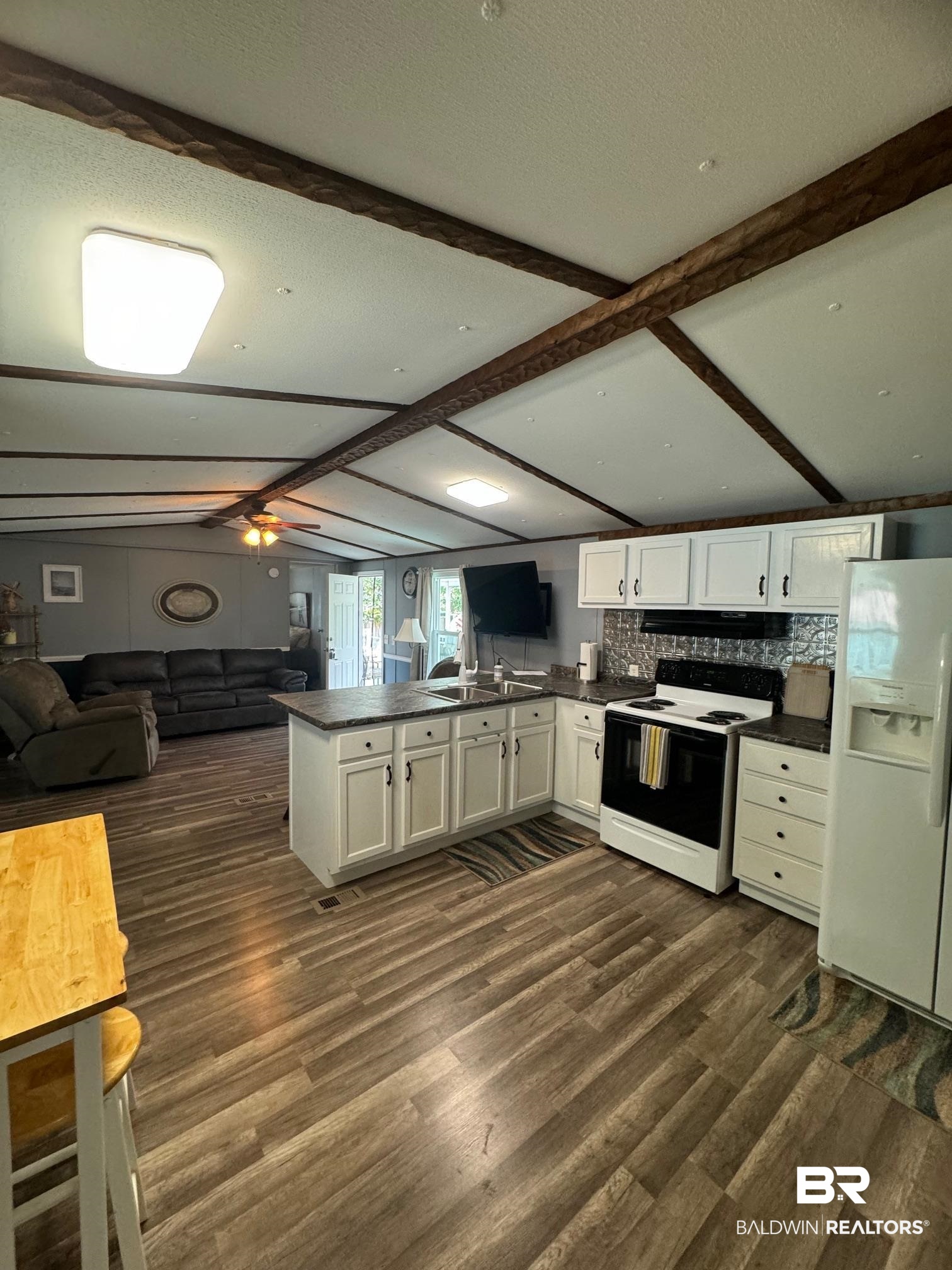 1420 Ridgewood Circle Lillian, AL 36549 - Photo 6 of 41 Kitchen featuring white appliances, kitchen peninsula, white cabinets, and dark hardwood / wood-style floors
