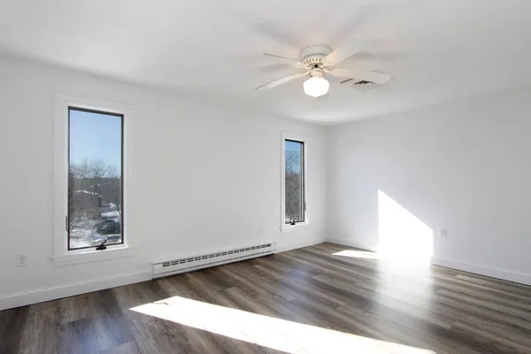 a view of an empty room with wooden floor and a window