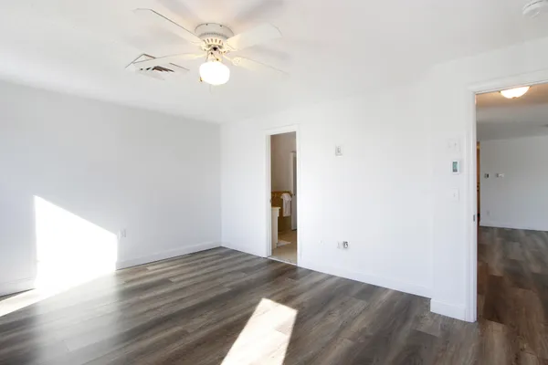 an empty room with wooden floor and fan