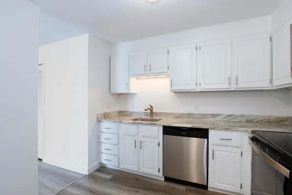 a kitchen with stainless steel appliances granite countertop white cabinets sink and dishwasher