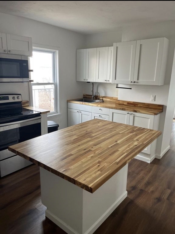 26 Edgeworth Street, Unit 1 Worcester, MA 01605 - Photo 1 of 13 a room with granite countertop a stove a sink dishwasher and wooden cabinets
