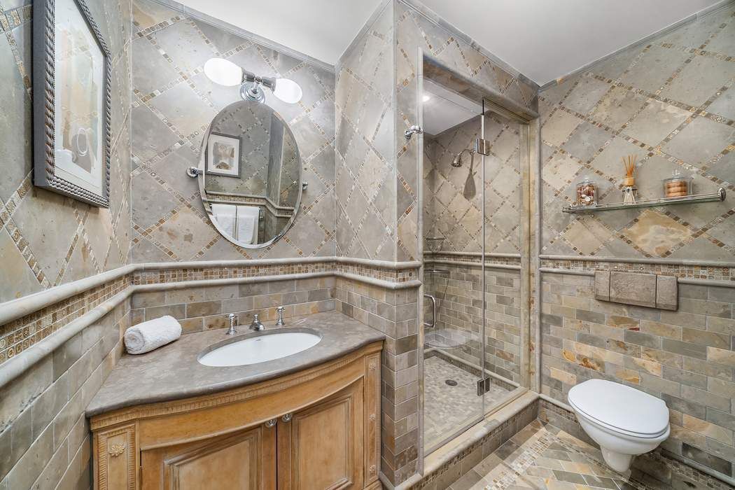 530 East 76th Street, Unit 22CDEG Manhattan, NY 10021 - Photo 24 of 31 a bathroom with a granite countertop sink toilet mirror vanity and bathtub