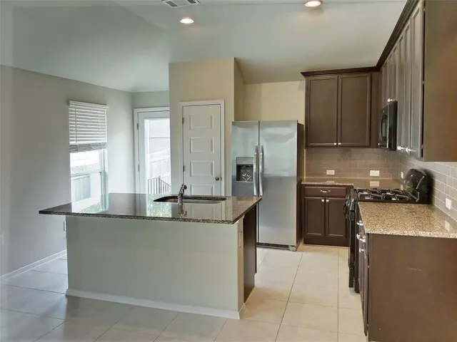 a kitchen with stainless steel appliances granite countertop a sink a stove and a refrigerator