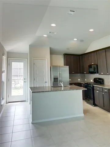 a kitchen with stainless steel appliances granite countertop a stove a sink and a refrigerator