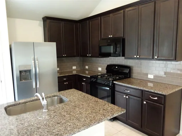 a kitchen with granite countertop stainless steel appliances and wooden cabinets