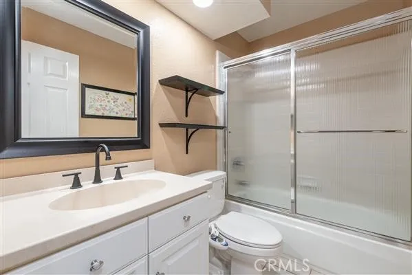 a bathroom with a shower sink vanity mirror and toilet