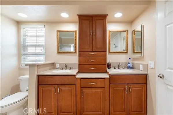 a bathroom with a granite countertop sink a toilet a mirror and a shower