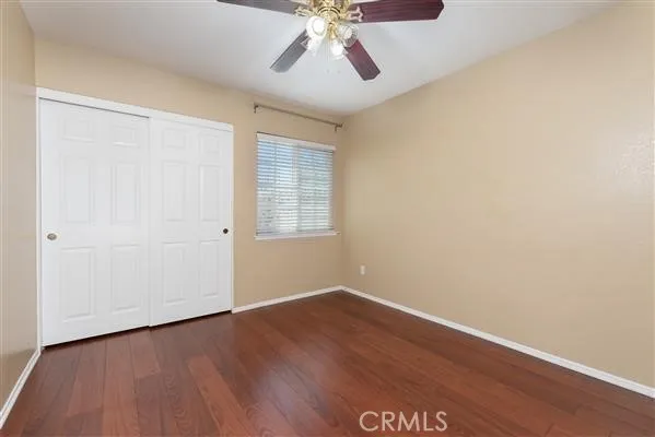 an empty room with wooden floor chandelier fan and windows